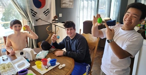 Two teenage boys and a little boy dying easter eggs