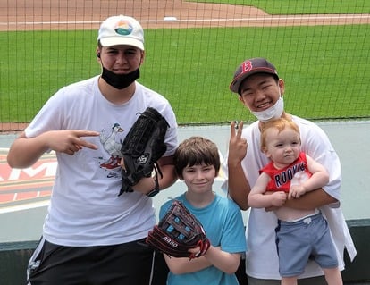 Two teenage boys and two little boys at baseball field