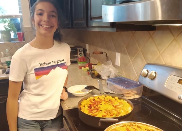 Spanish teenager standing by two fresh paellas