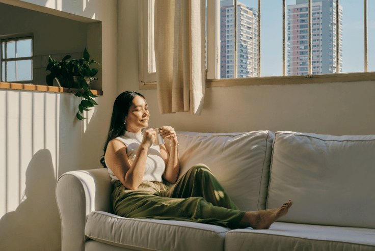 woman sitting on couch with tea looking serene