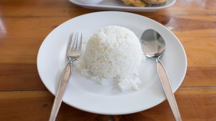 A place with a scoop of rice and a fork and spoon