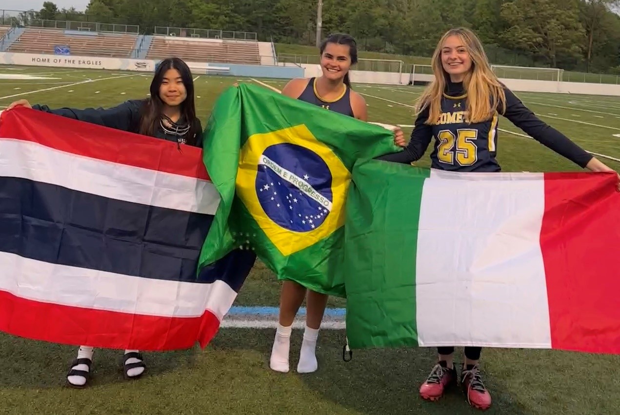 three teen girls holding country flags: Thailand, Brazil, Italy