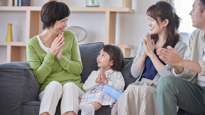 Asian family teaching child to put hands together to show respect and gratitude