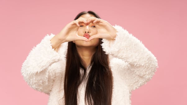 Asian teen girl creating a heart with hands