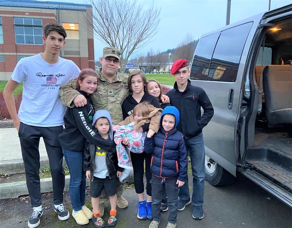 family hugging military dad