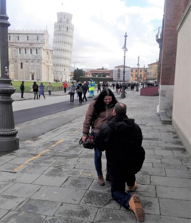 Bob on one knee proposing to Carla; Tower of Pisa in background