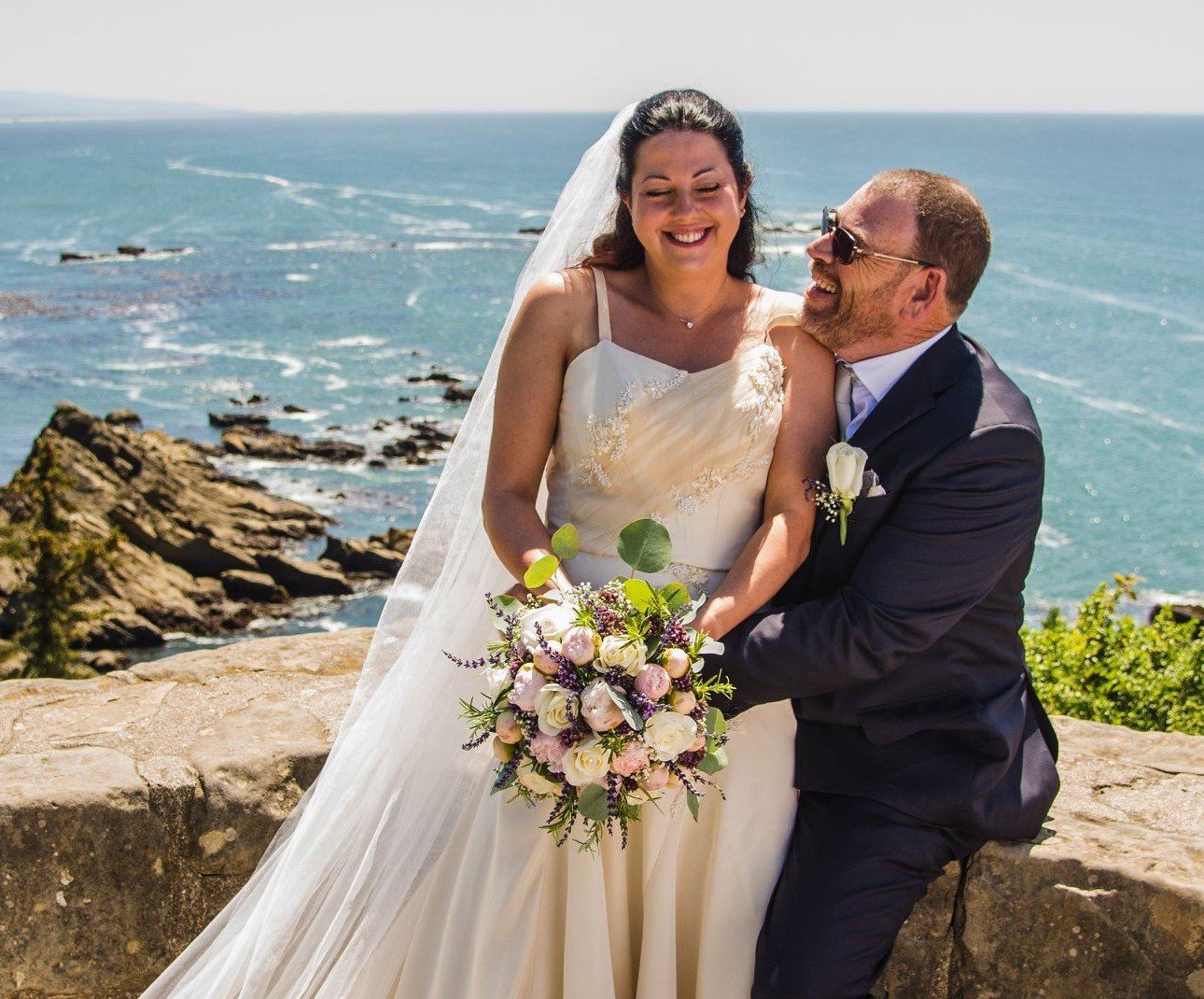 bride and groom with ocean behind