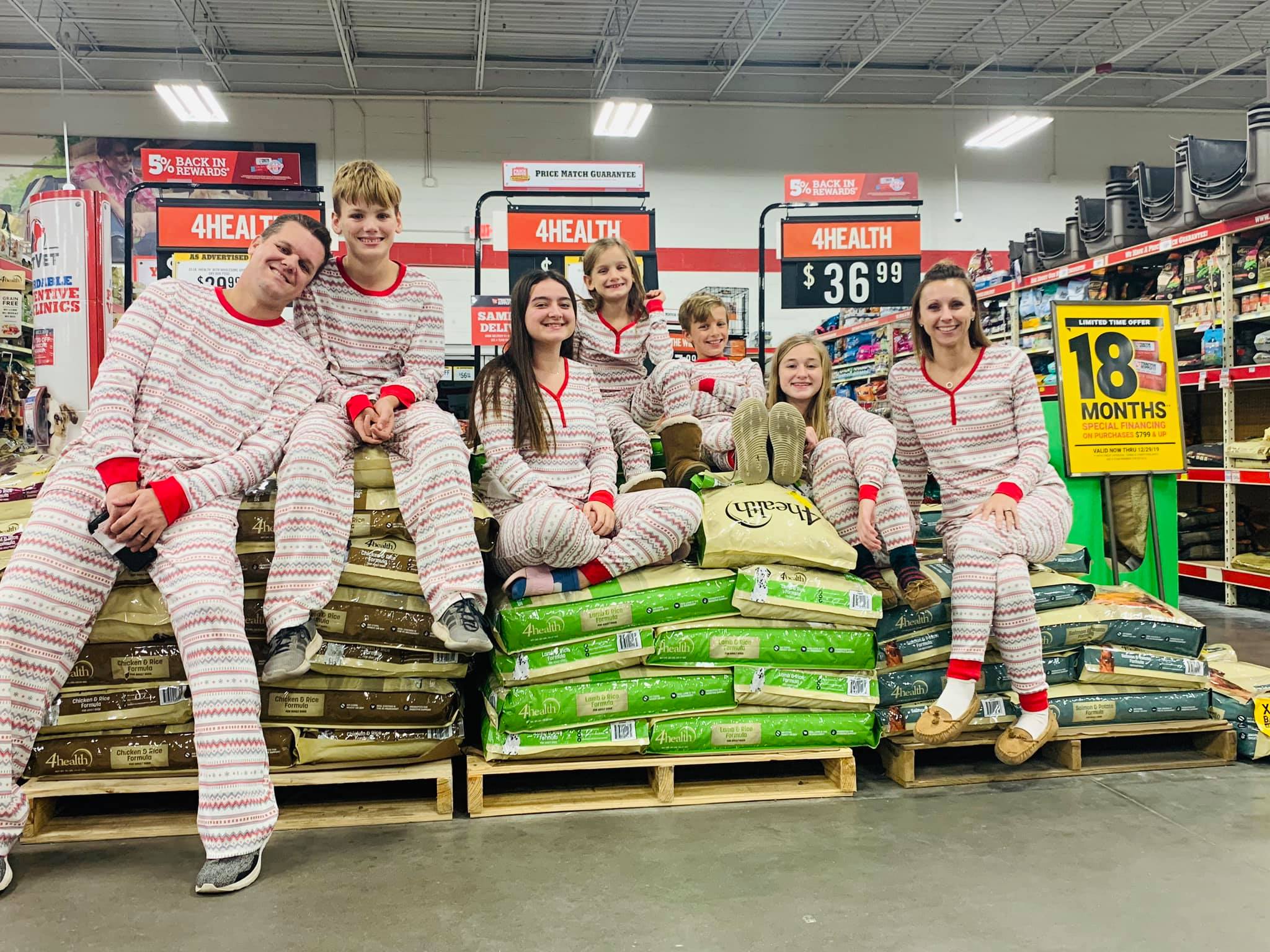 Family in matching pjs sitting on stacks of dog food bags