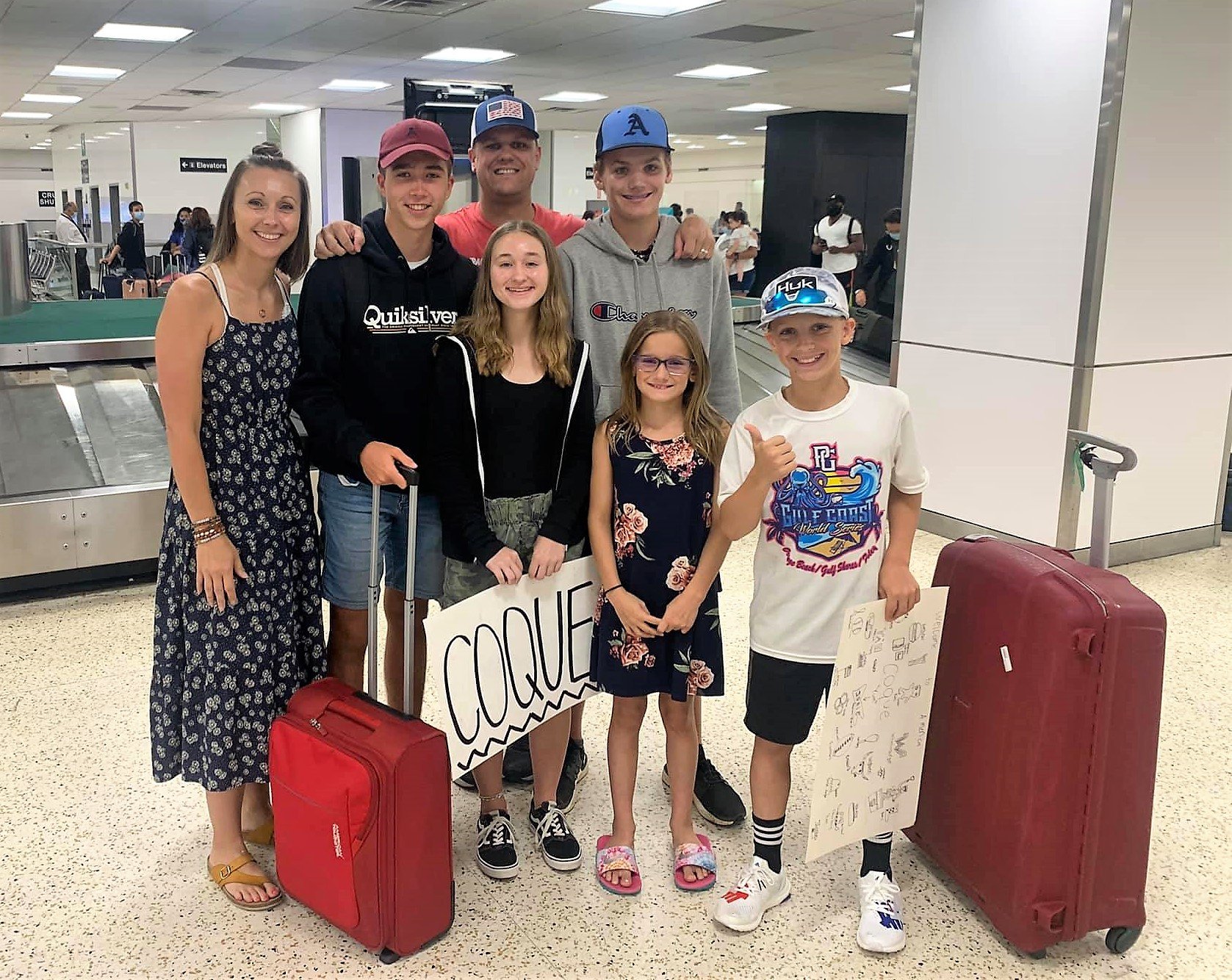 family standing with exchange student at airport