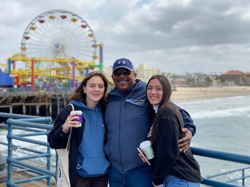 dad and two teen girls in front of amusement park