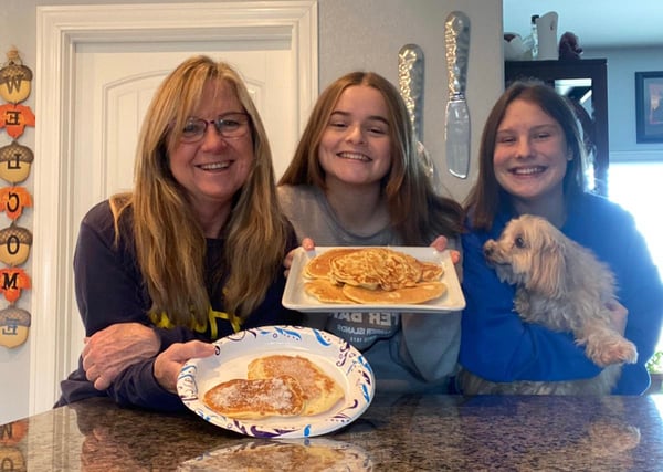 Mother and two daughters holding plates of German Apple Pancakes