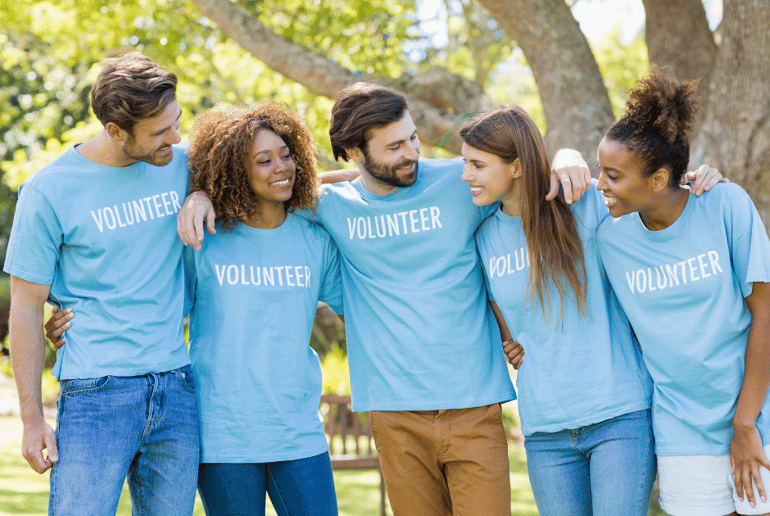 Group of people wearing volunteer t-shirts with their arms around each other
