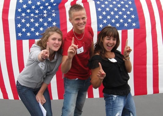 three teens in front of American flags