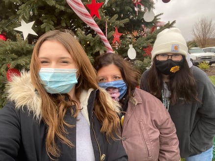 three women wearing masks in front of a Christmas tree