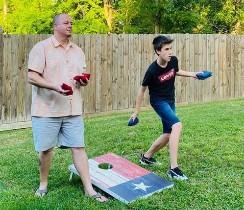 Dad and teen boy playing corn hole