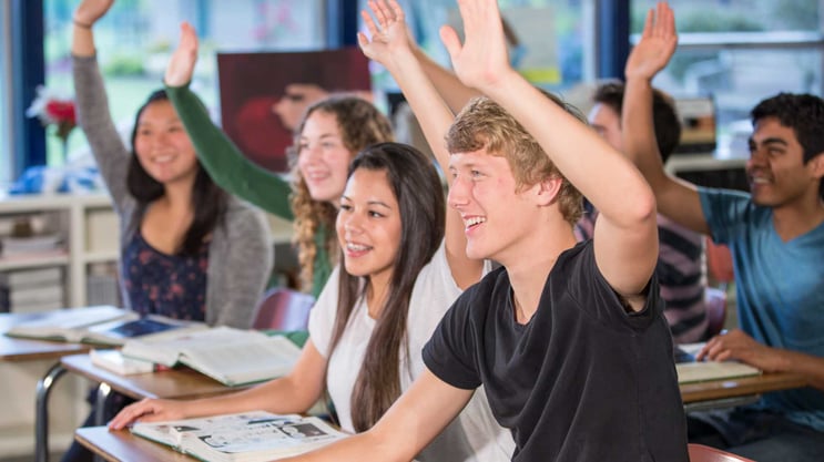 High school students raising their hands in class