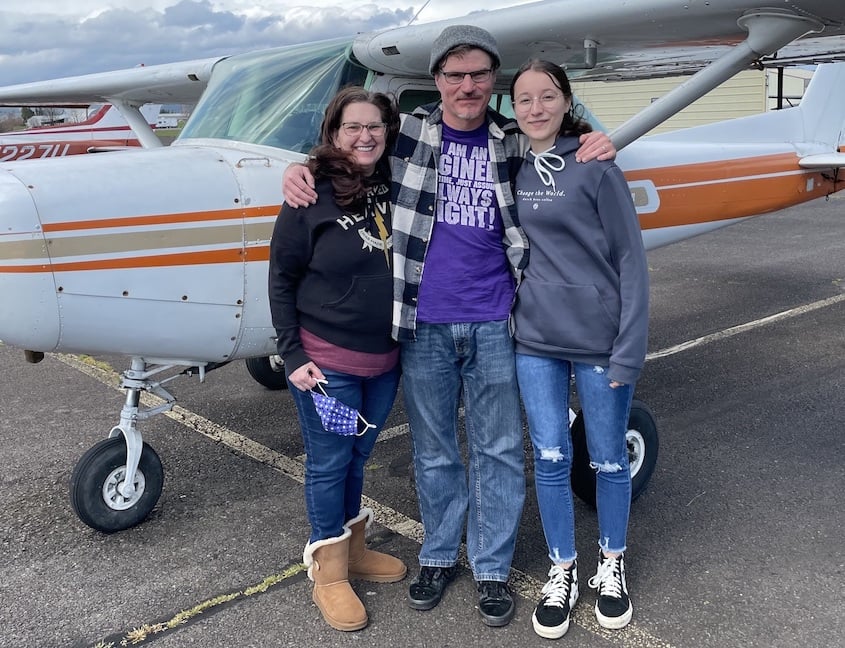 parents and daughter standing in front of a sea plane