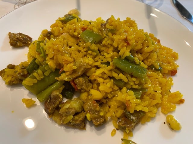 a plate of Spanish paella with meat and vegetables