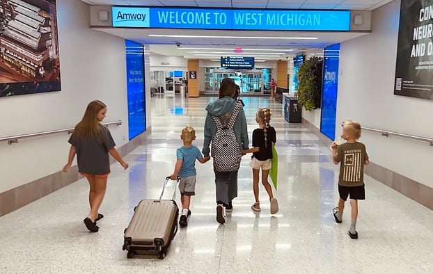 young kids holding hands with teen at airport