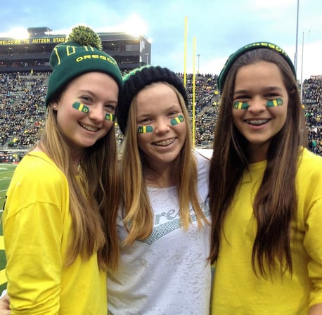 three teen girls with face paint at a college football game