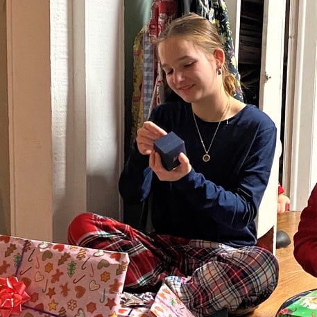 Jana smiling and opening a Christmas gift