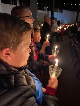 Jana and host brothers holding candles at church