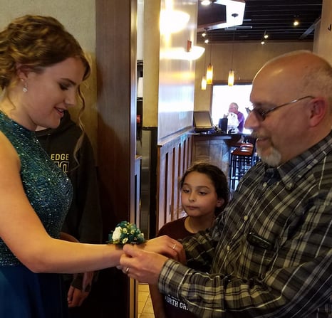 Dad putting corsage on teen girl's wrist