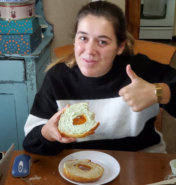 girl giving thumbs up and eating bagel