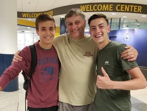 Dad with arms around the shoulders of two teen boys