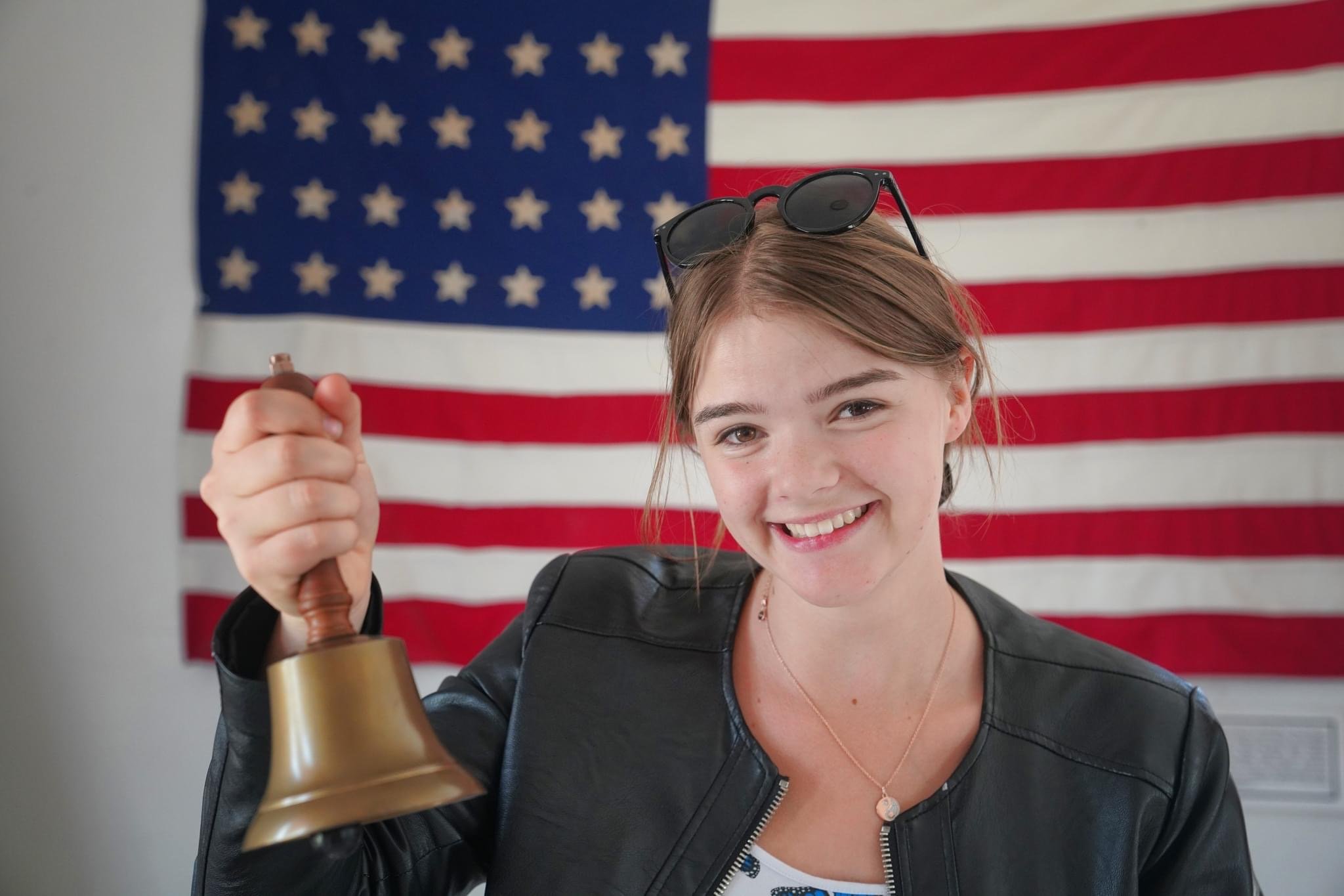 girl holding bell with flag in background