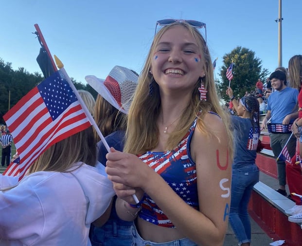 teen girl dressed in red, white, & blue holding flag