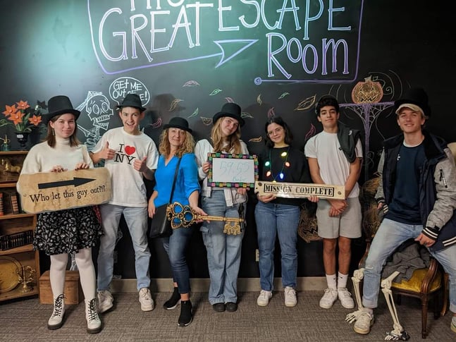 woman and teens with escape room signs