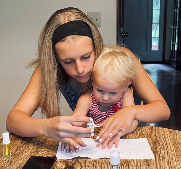 teen painting nails with toddler in lap