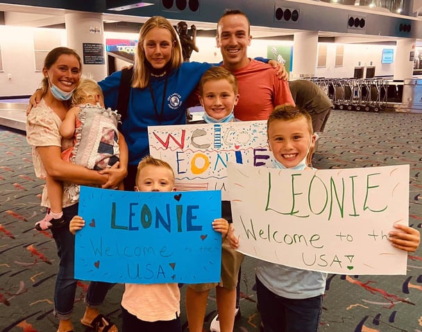 family at airport with welcome signs