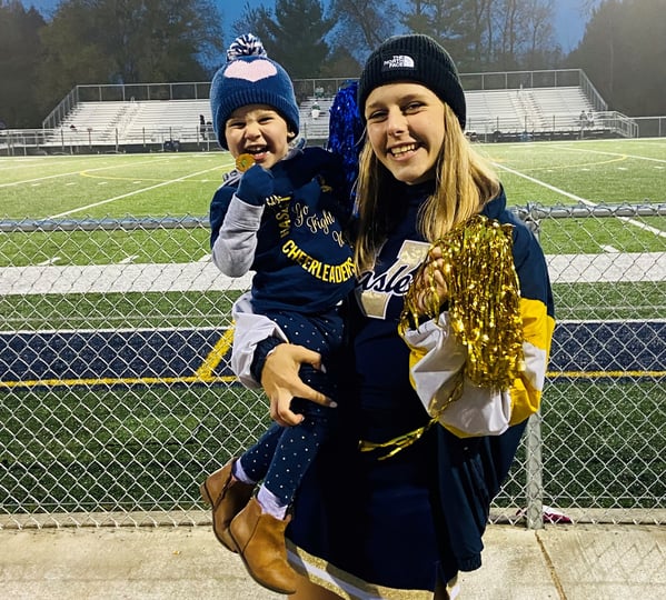 cheerleader holding laughing young child