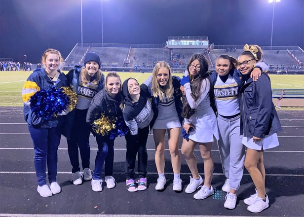 group of smiling teens at football game