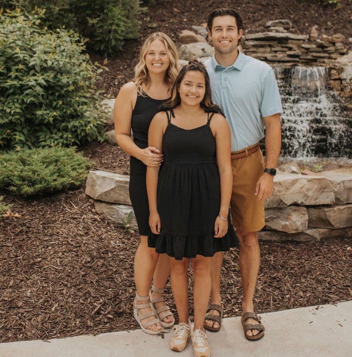 couple with teen girl in front of waterfall