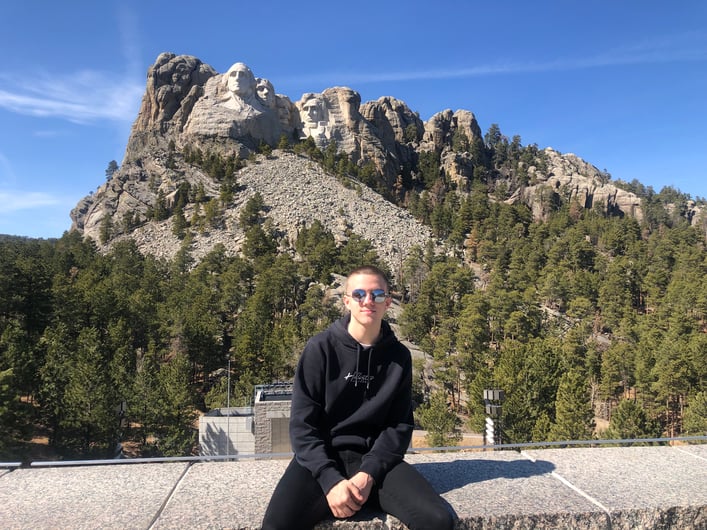 boy sitting on wall with Mt. Rushmore behind