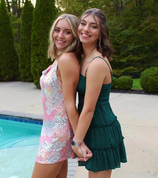 two girls in formal dresses in front of a pool
