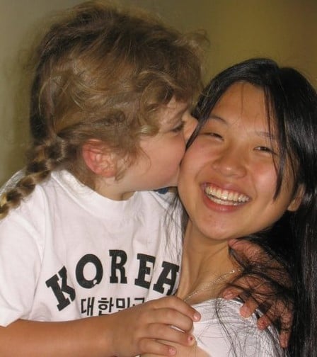 young girl kissing Korean exchange student's cheek