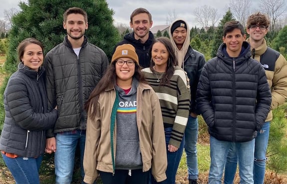 Eight international exchange students smiling in a group photo outdoors