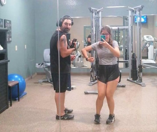 Dad and teen girl in gym comparing biceps