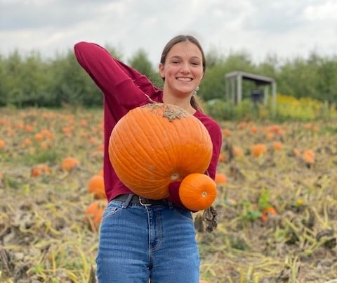 girl holding a pumpkin in a field