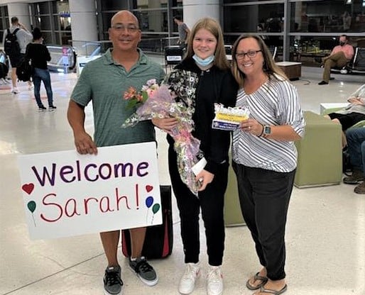 host parents and student with welcome sign at airport