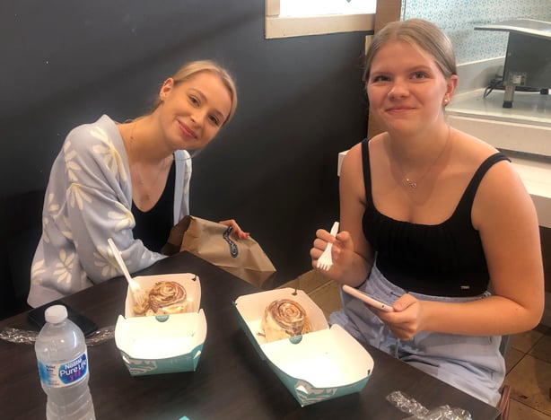 two teen girls eating cinnamon rolls