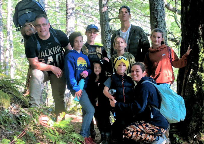 Parents and eight children posing for a family photo in the forest