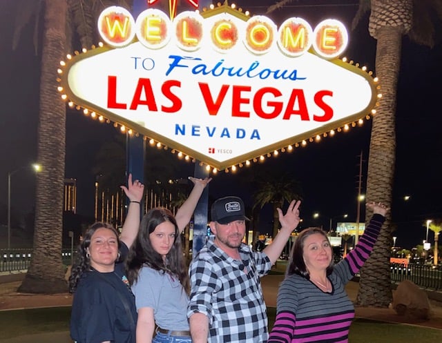 Parents and two daughters in front of Welcome to Las Vegas sign