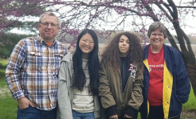 smiling parents with two asian teenagers they are hosting