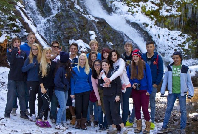 woman and group of teens in front of waterfall
