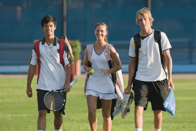 Three teenagers walking with tennis rackets